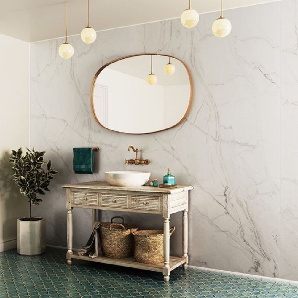 Lifestyle image of the Showerwall Laminate Ocean Marble 2440mm x 579mm Proclick Hydrocore Wall Panel - SW65 across a large wall, situated behind a traditional piece of furniture with countertop basin, wall mounted brass taps, and brass oval mirror